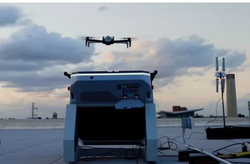 A Skydio X10 drone hovering above its rooftop dock at dusk.